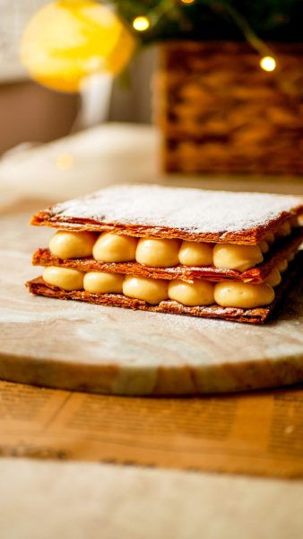 Mille-feuille szelet fadeszkán, háttérben karácsonyi fények